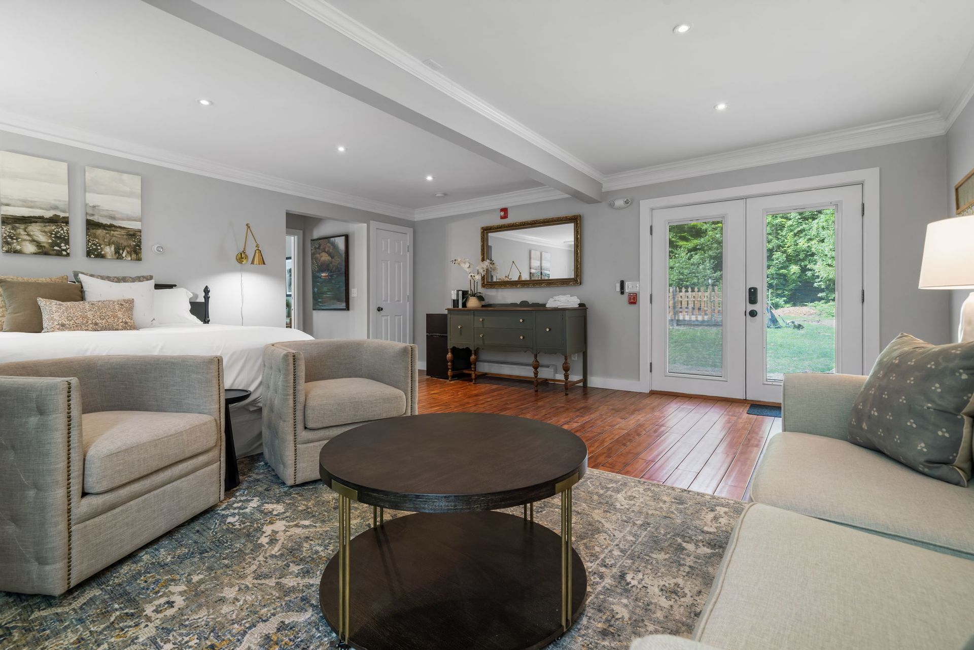 A living room with a couch , chairs , a coffee table and a bed.