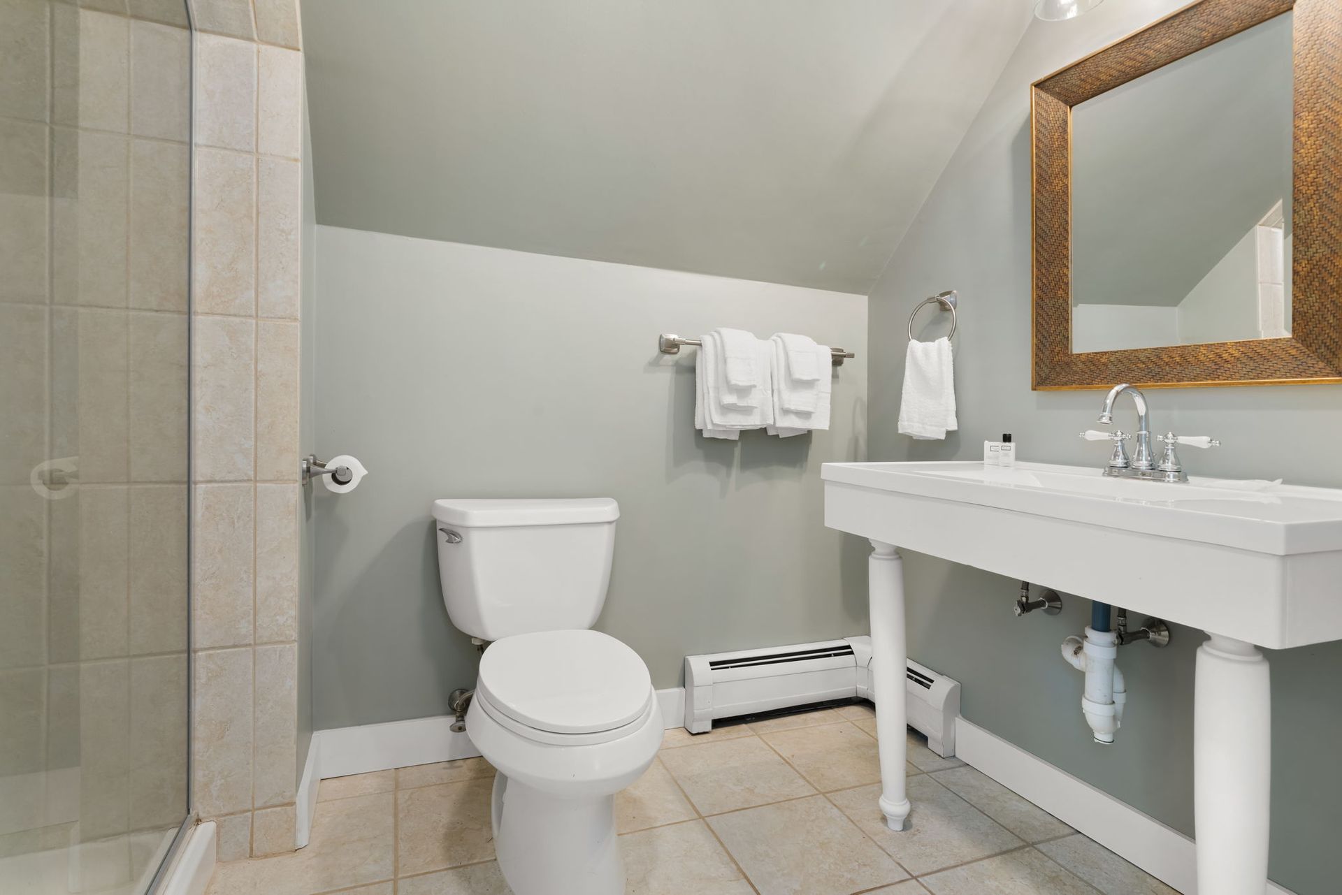 A bathroom with a toilet , sink , mirror and shower.