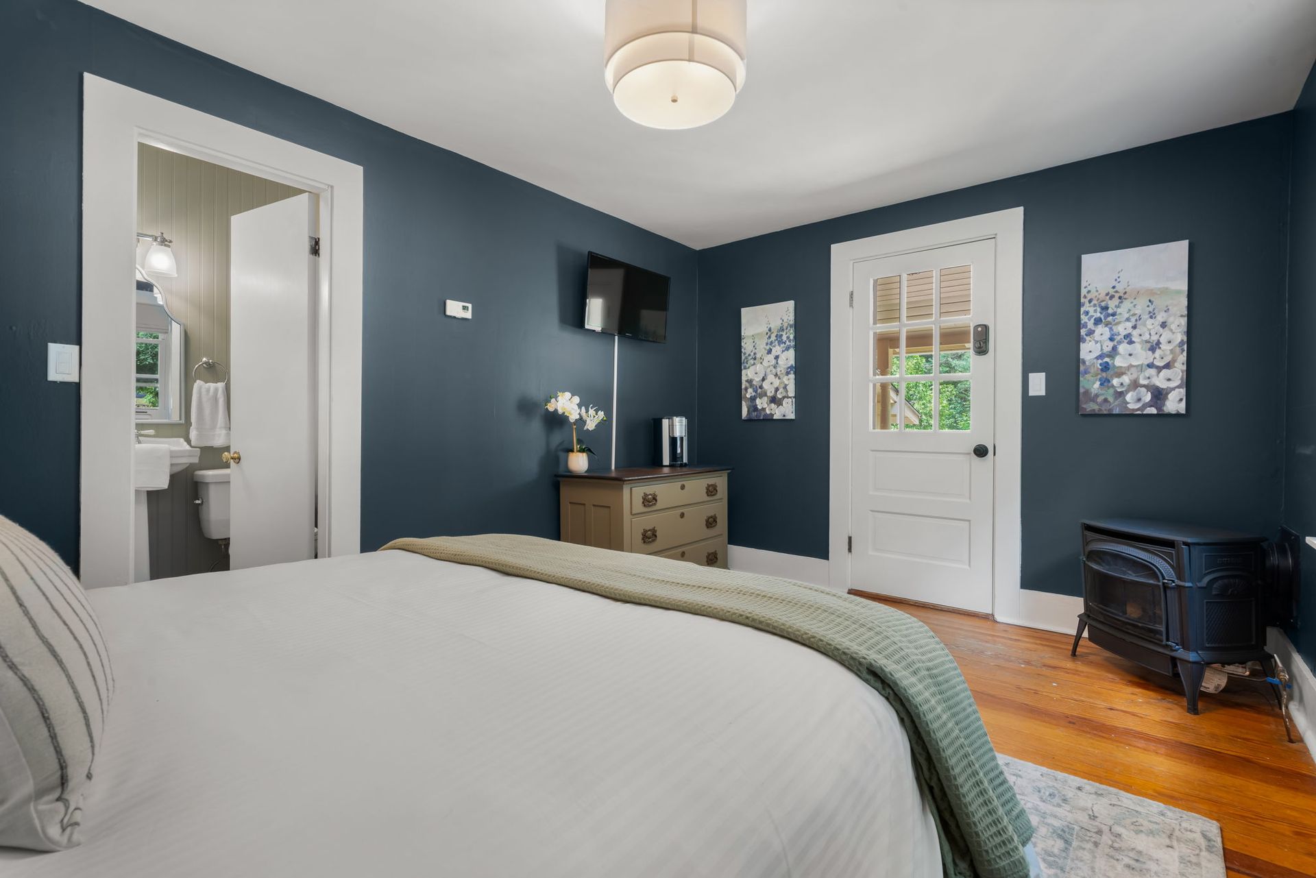A bedroom with a bed , dresser , nightstand and television.