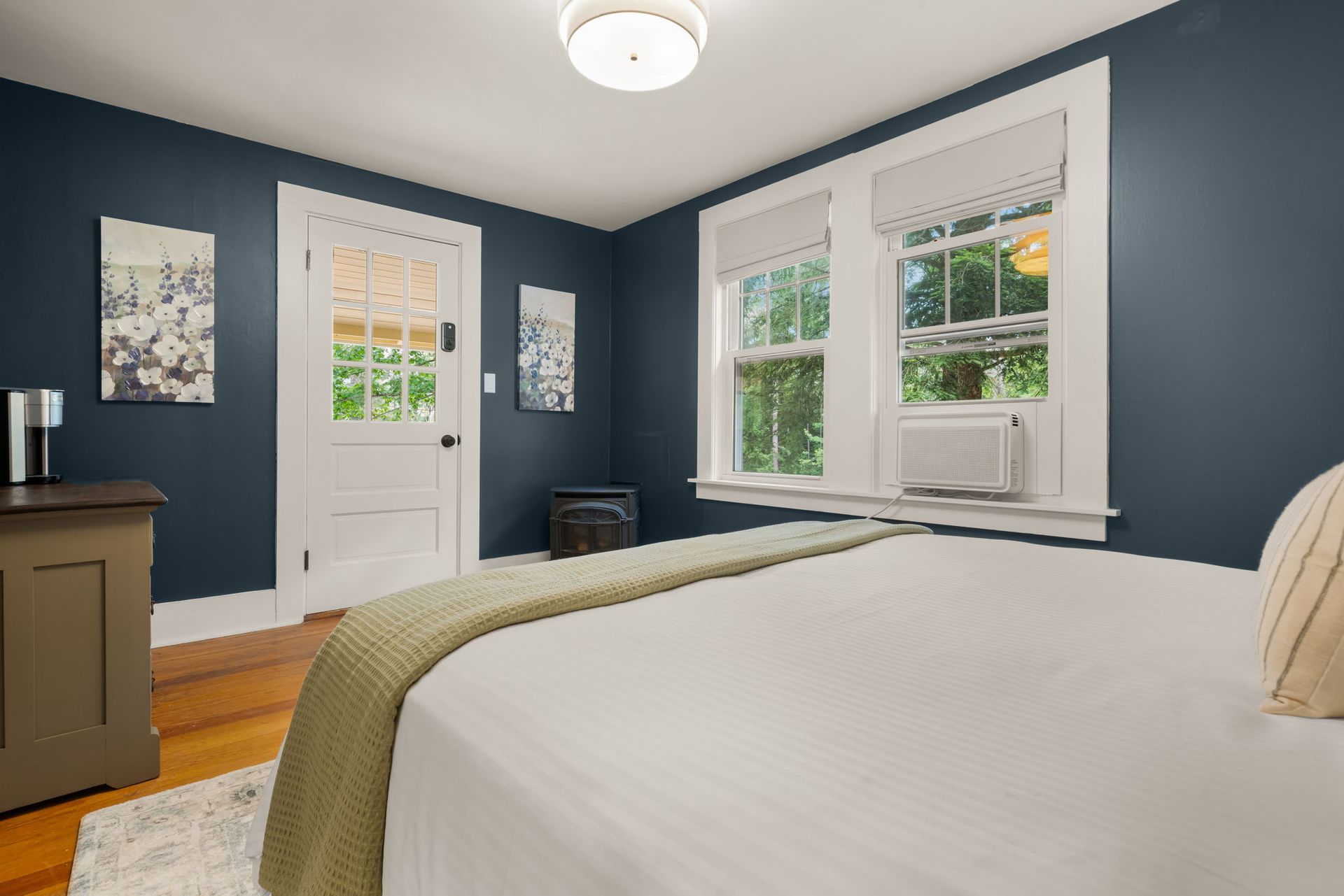 A bedroom with a bed , dresser , and two windows.