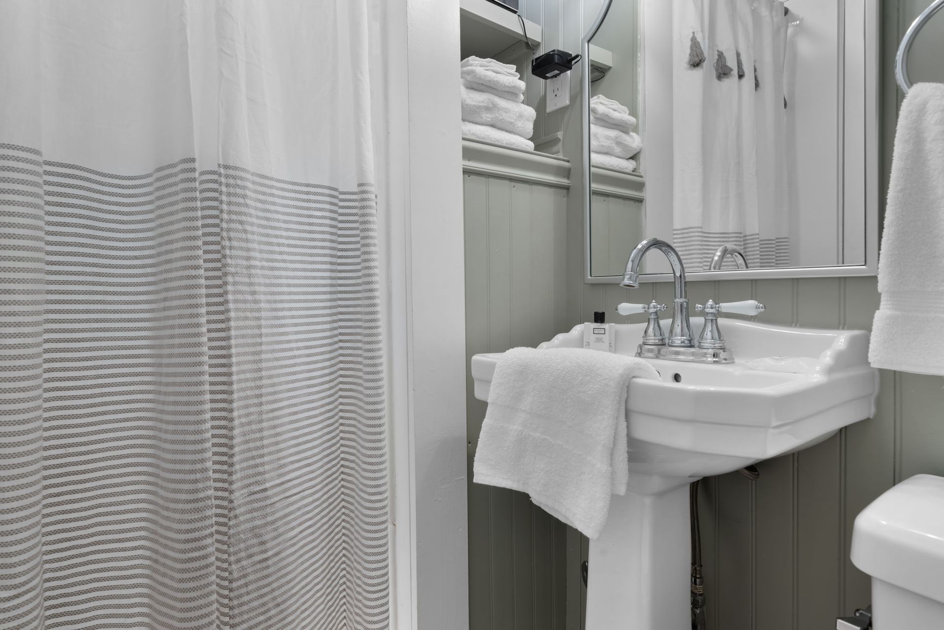 A bathroom with a sink , toilet , shower curtain and mirror.