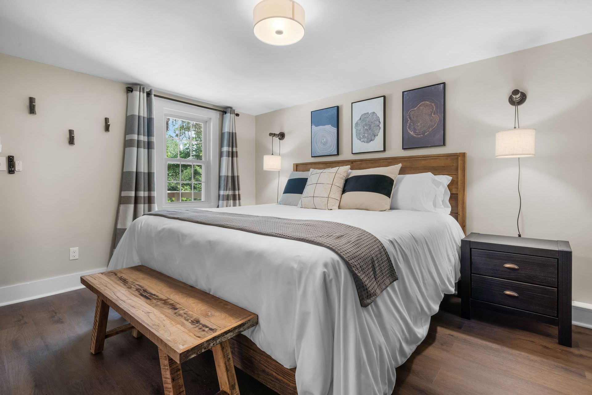 A bedroom with a king size bed , nightstand , and bench.