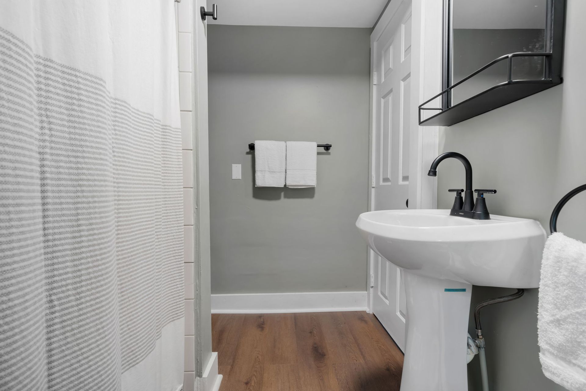 A bathroom with a sink , mirror and shower curtain.