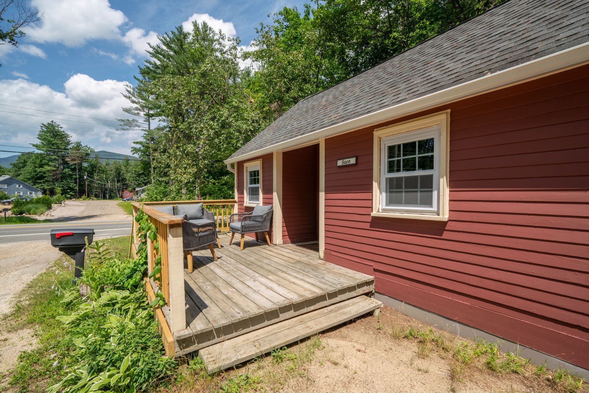 A red house with a wooden deck and chairs on it.