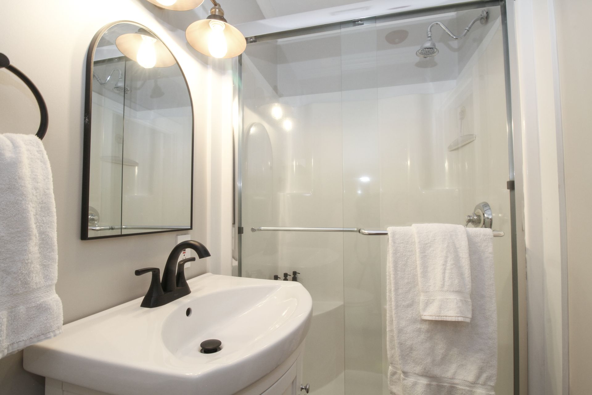 A bathroom with a sink , mirror and shower.