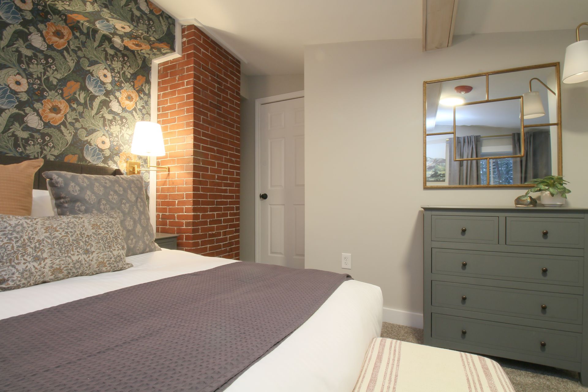 A bedroom with a bed , dresser and mirror.