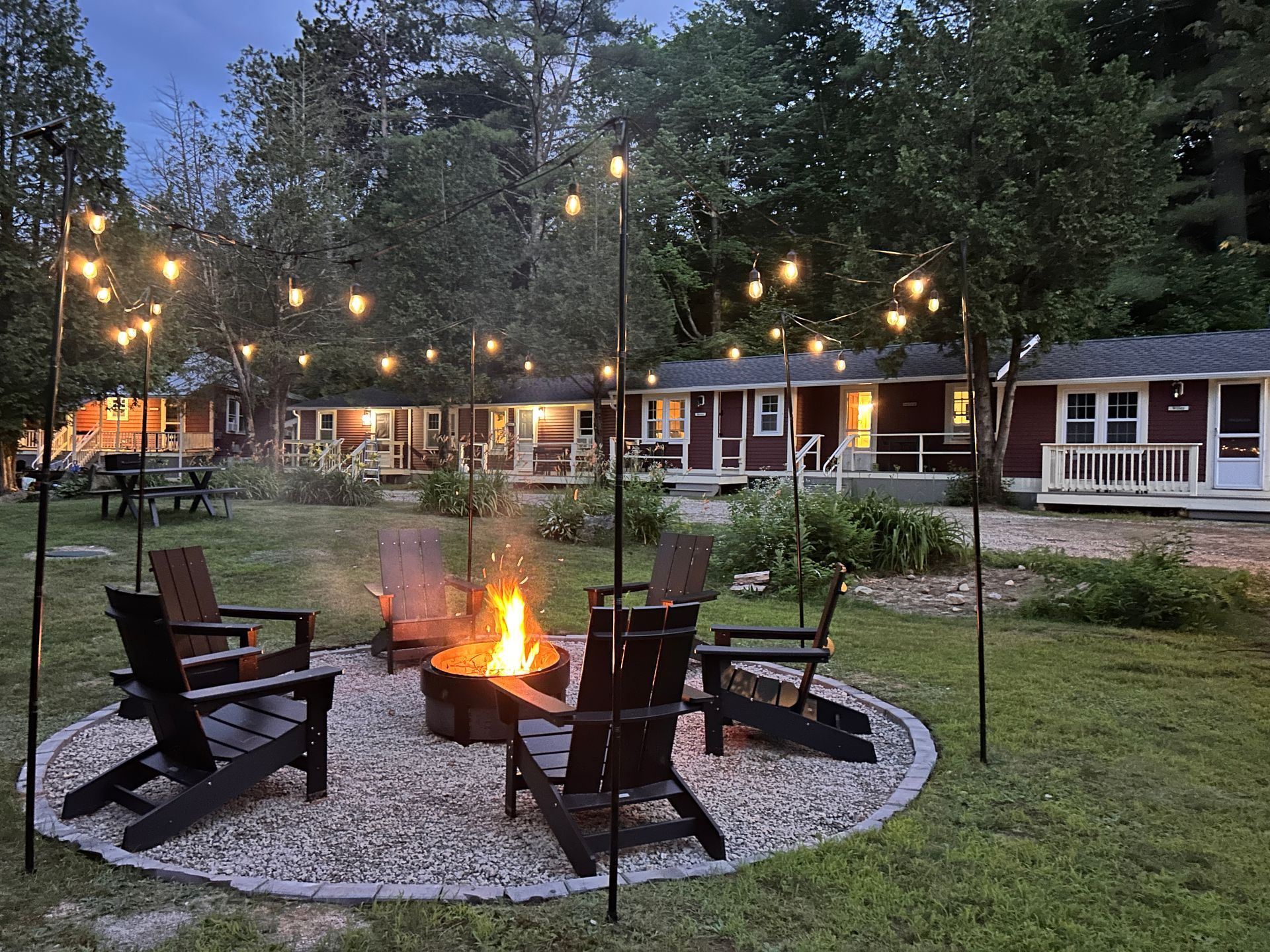 There is a fire pit in the middle of the yard with chairs around it.