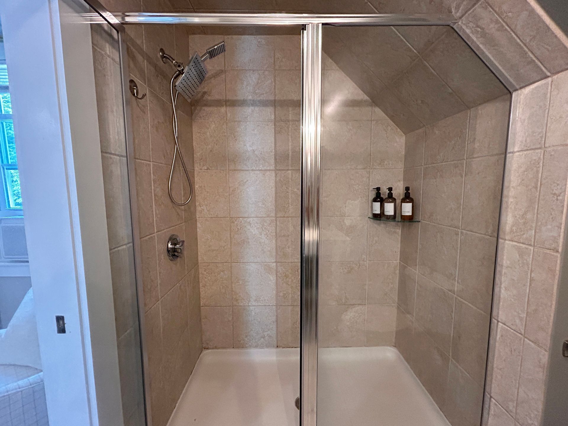 A bathroom with a walk in shower and a glass door.