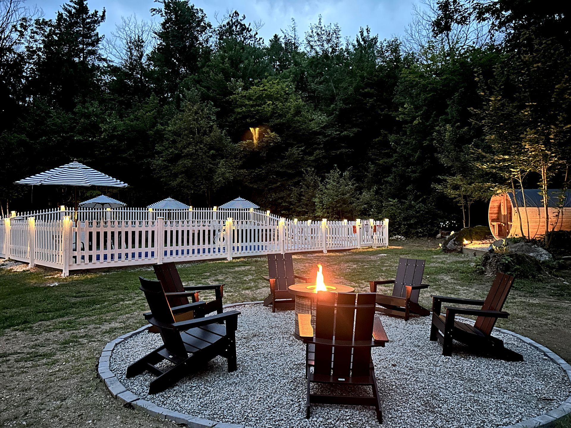 A group of chairs are sitting around one of two fire pits.