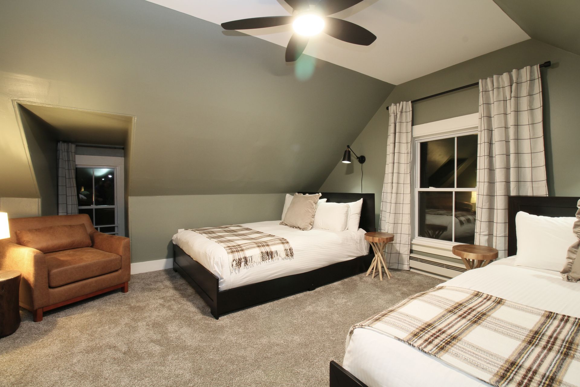 A bedroom with two beds , a chair and a ceiling fan.