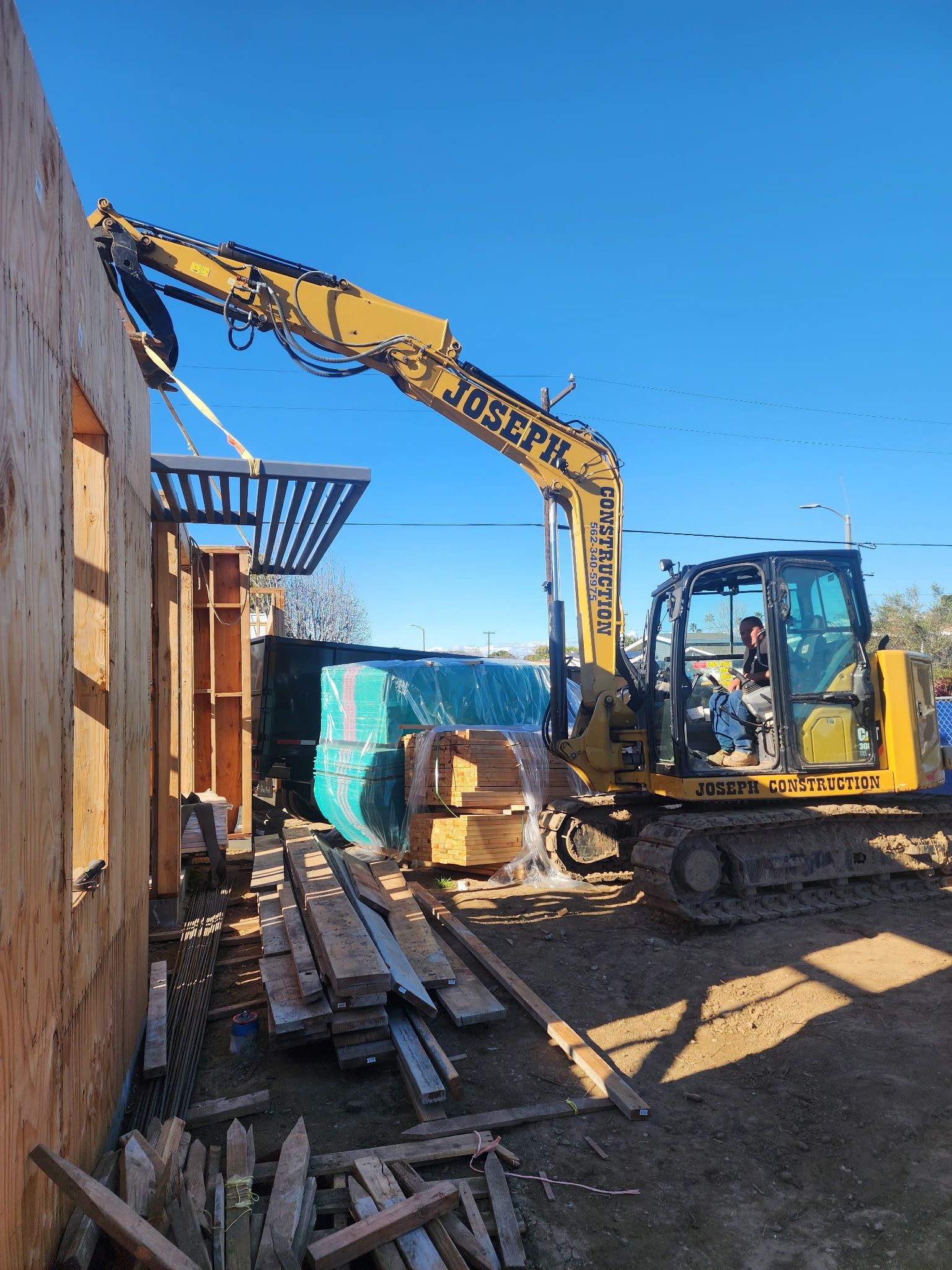 A yellow dump truck is parked in front of a building being demolished.