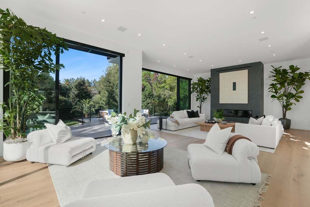 Modern living room with white sofas, large windows, and an outdoor view.