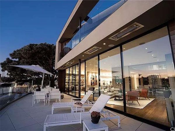 Modern home with a balcony and large glass windows. Outdoor seating and views.