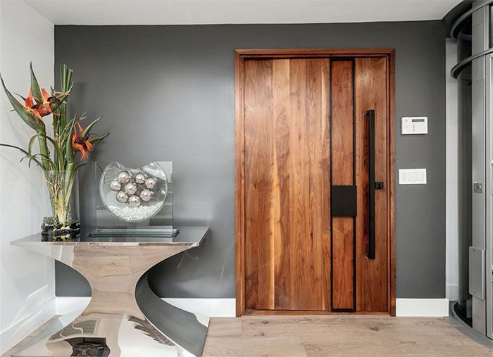 A hallway with a wooden door and a glass table.