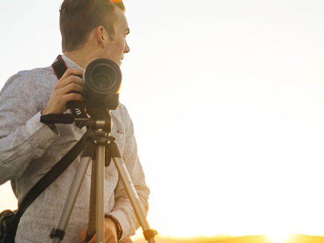 Man taking photo with digital camera on tripod