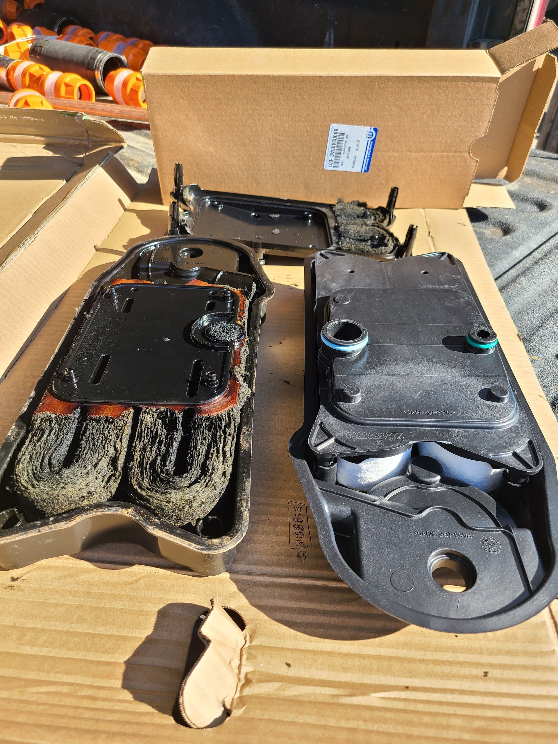 Charred disassembled electronic parts on cardboard, with melted black and gray components spread on a wooden surface. | Kingsley Auto Service