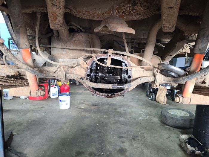 Undercarriage of a dusty off-road vehicle with exposed axle and suspension in a garage. | Kingsley Auto Service