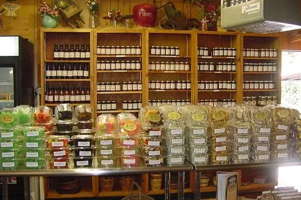 Store shelves filled with jars of various goods above a display table stocked with stacks of packaged treats and snacks.