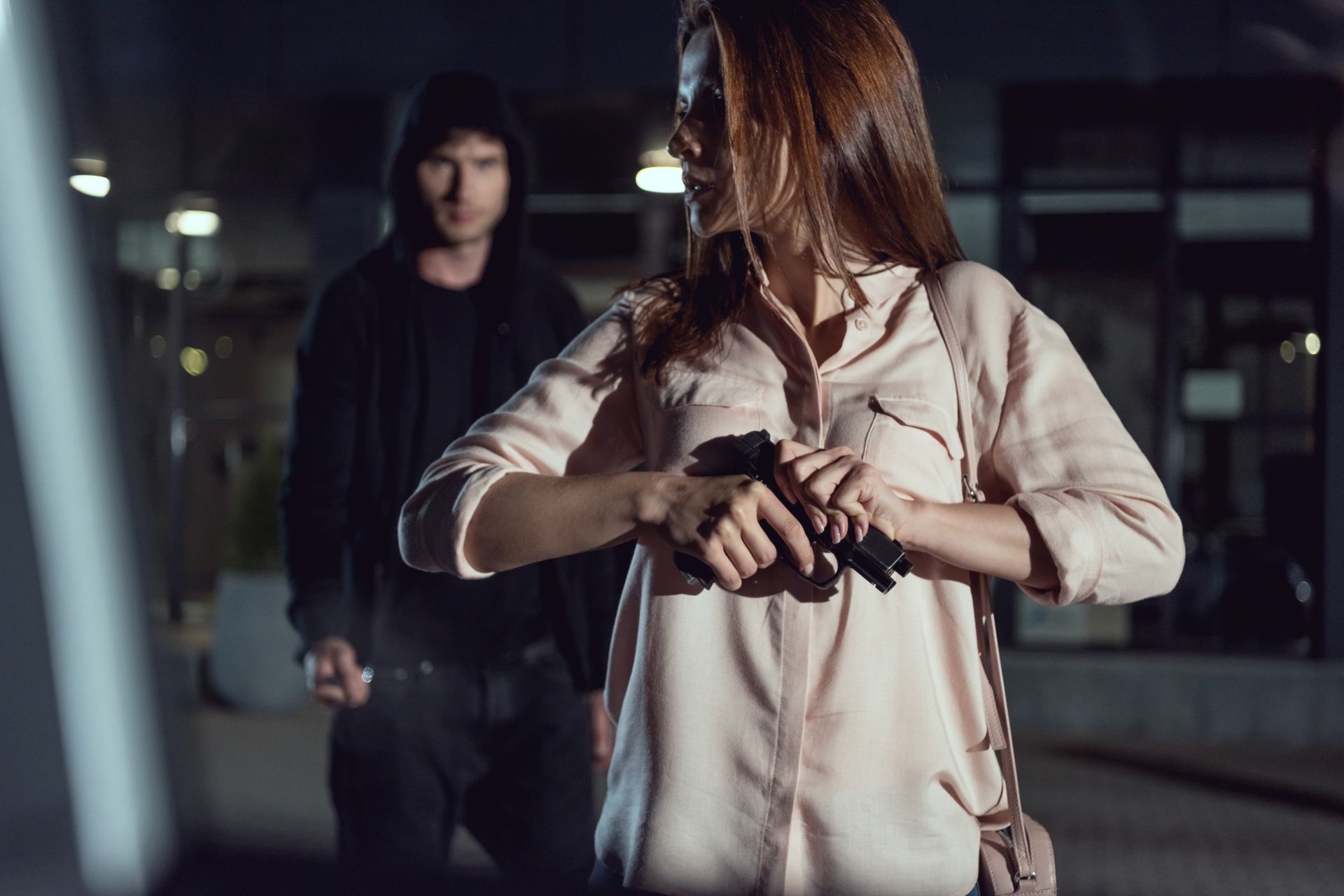girl locking and loading her gun with a robber behind her