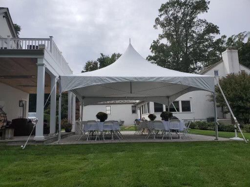 White tent set up on a grassy lawn with tables and chairs for an outdoor event.