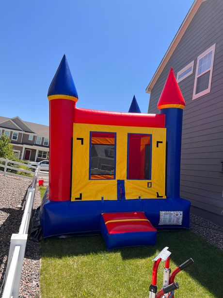 Colorful inflatable castle bounce house on green grass.