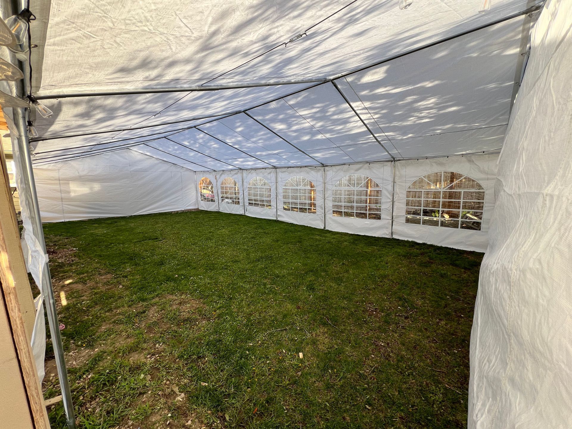 Inside view of a white tent with clear window panels and green grass floor.