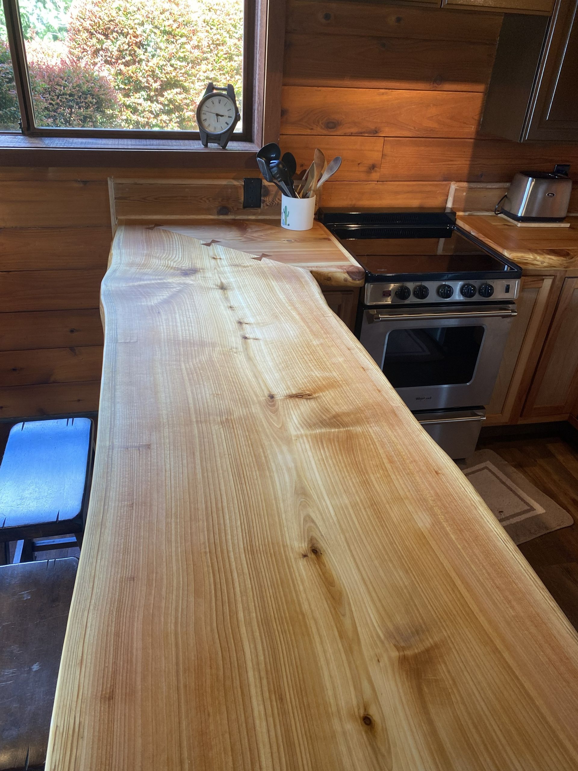 Wooden kitchen counter with stovetop, window, and kitchenware.