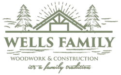 Logo for Wells Family Woodwork & Construction featuring a house frame, pine trees, and text.