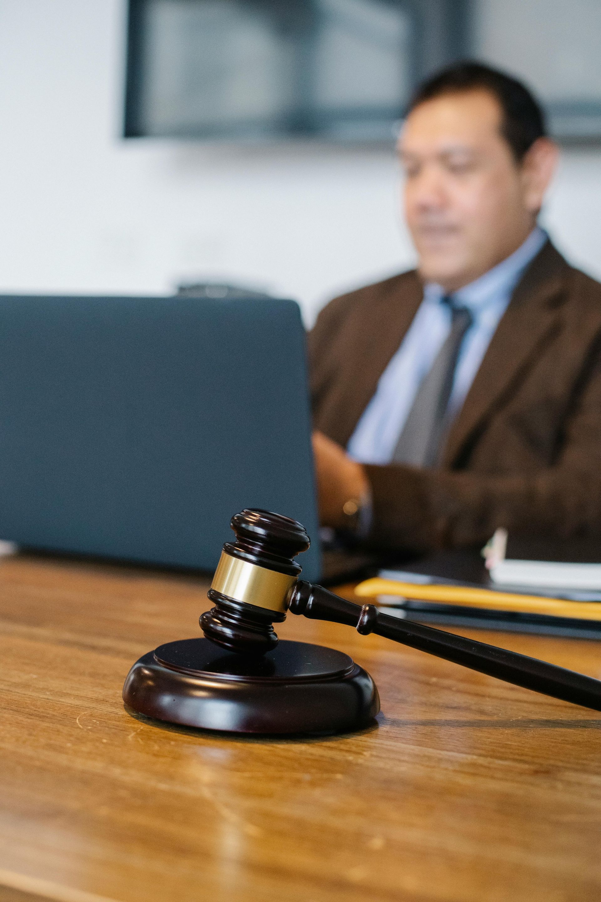 People reviewing contract and legal documents at a desk; includes gavel, laptop, and books.
