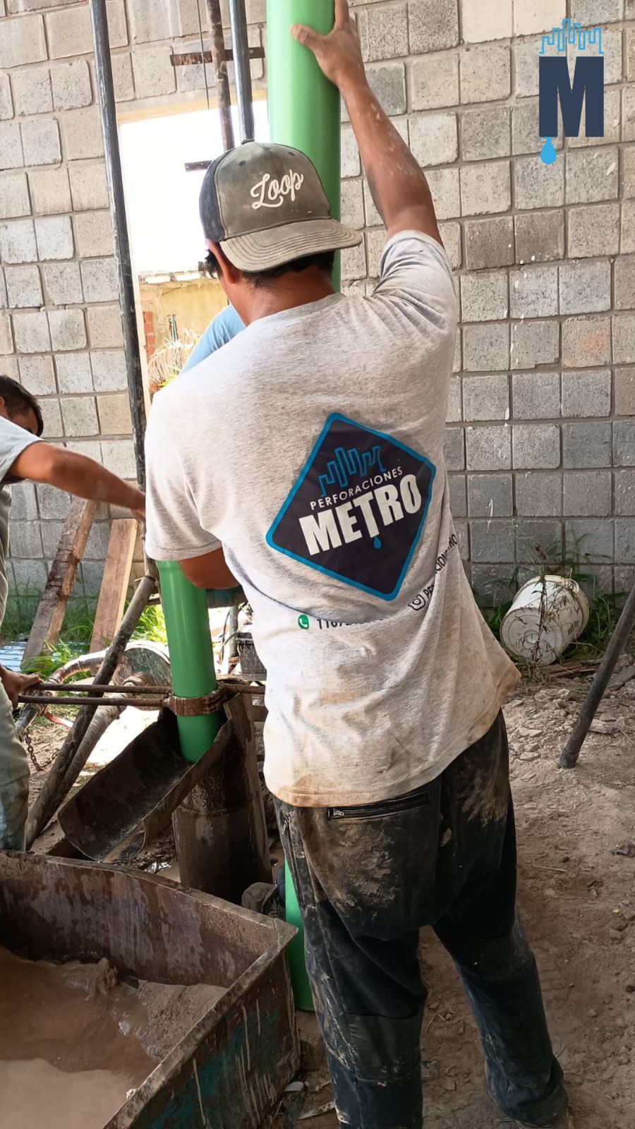 Un trabajador con ropa polvorienta levanta una tubería verde 