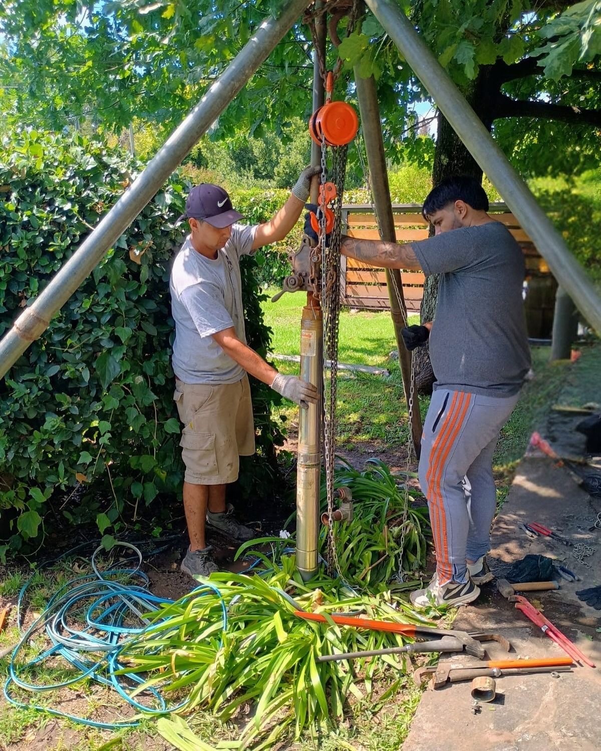 Dos personas utilizan un polipasto de trípode para instalar
