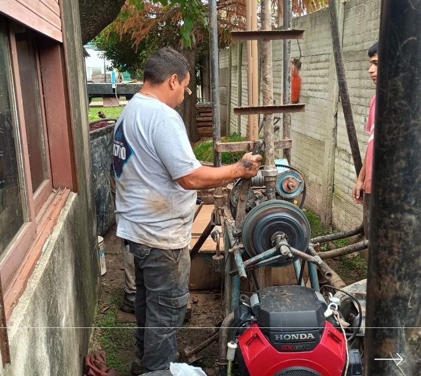 Un trabajador maneja una plataforma de perforación portátil con un motor Honda rojo junto a un edificio.