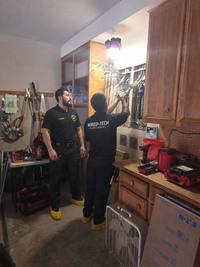 Technician inspecting an open electrical control panel with wires and circuit breakers