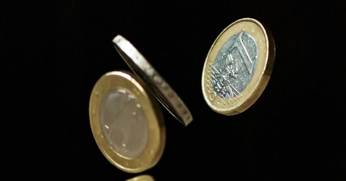 Twee bimetalen munten zweven in de lucht tegen een zwarte achtergrond.