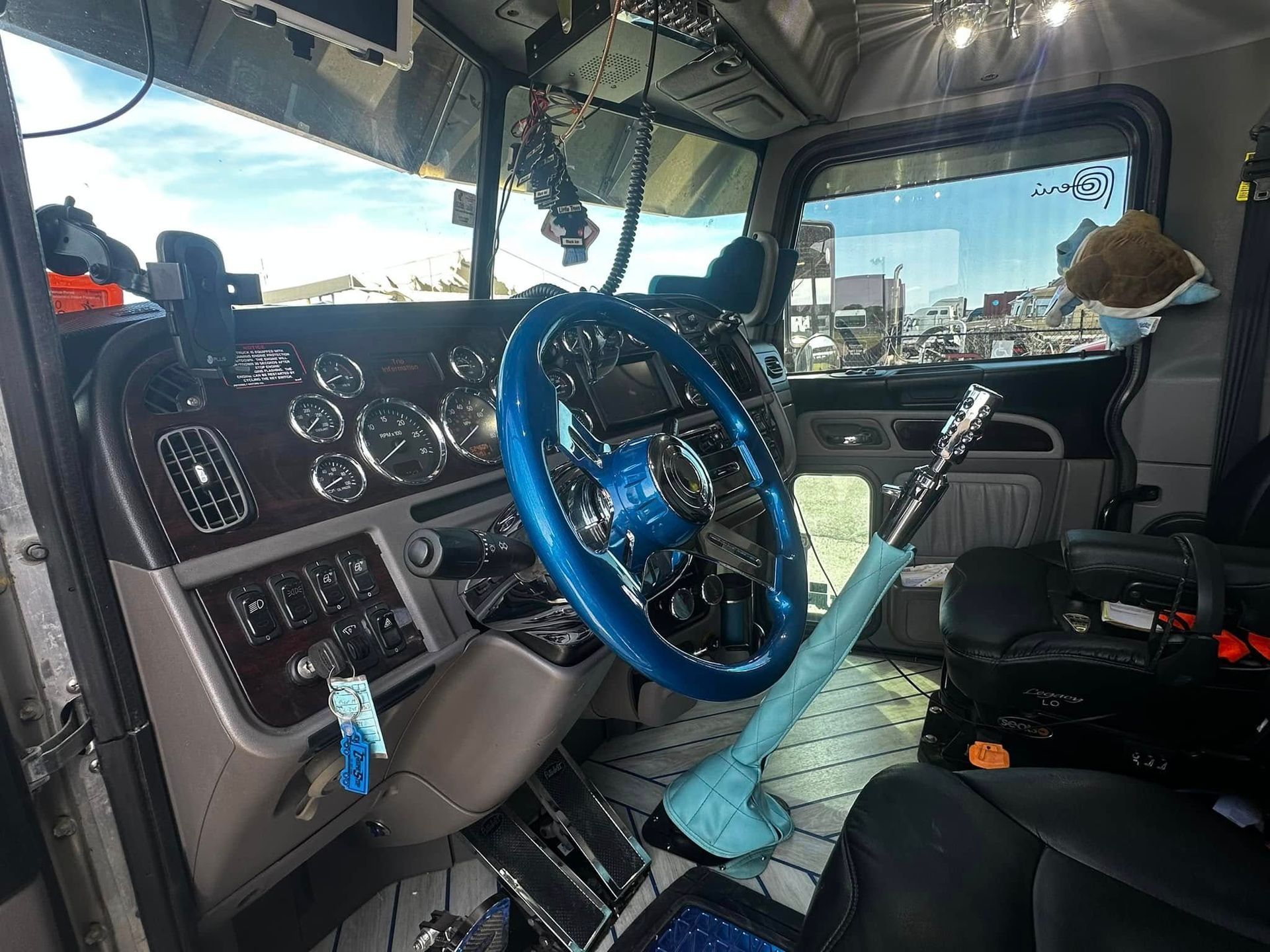 The interior of a semi truck with a blue steering wheel.