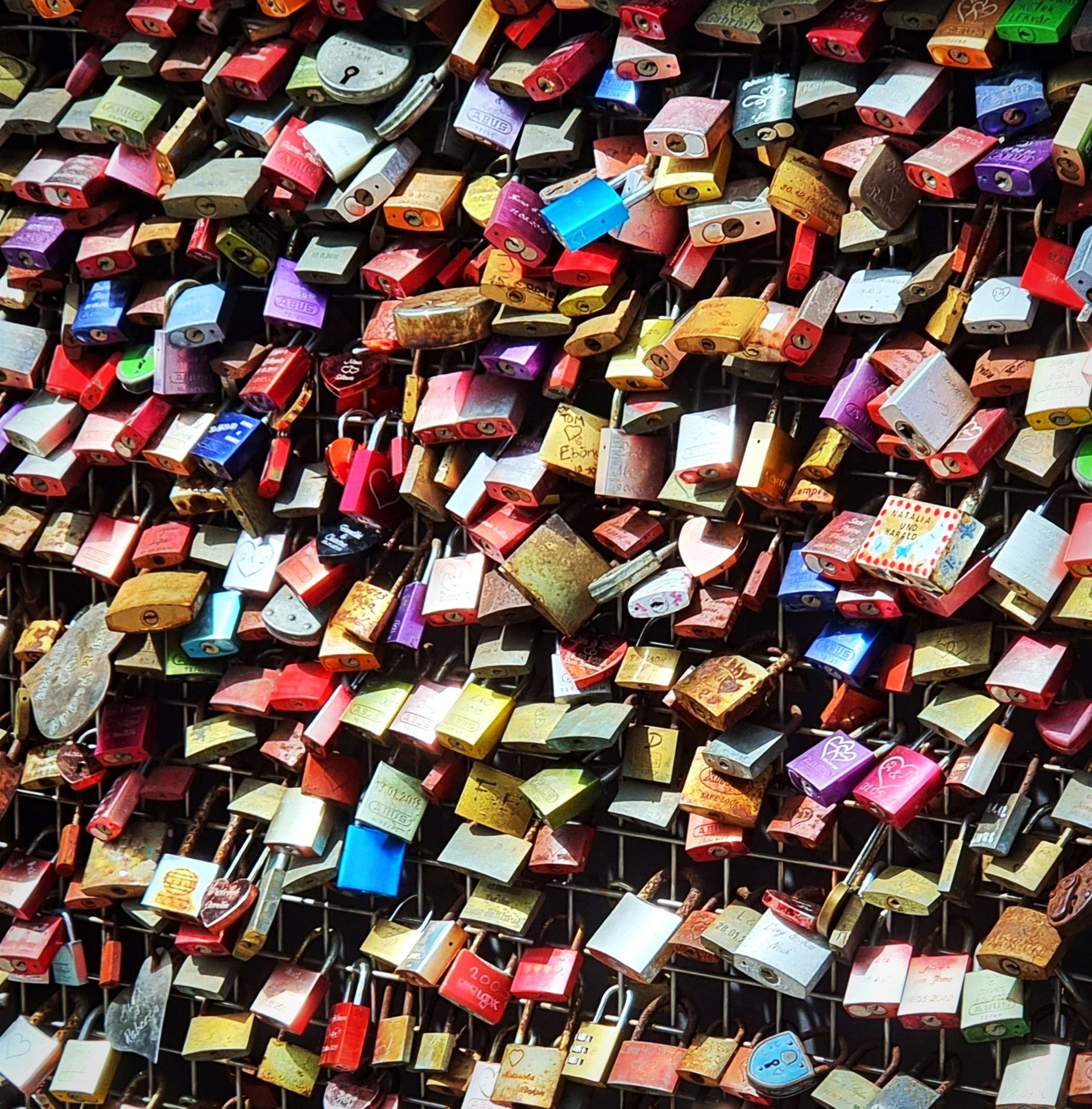 Hundreds of colorful padlocks tightly packed together on a fence