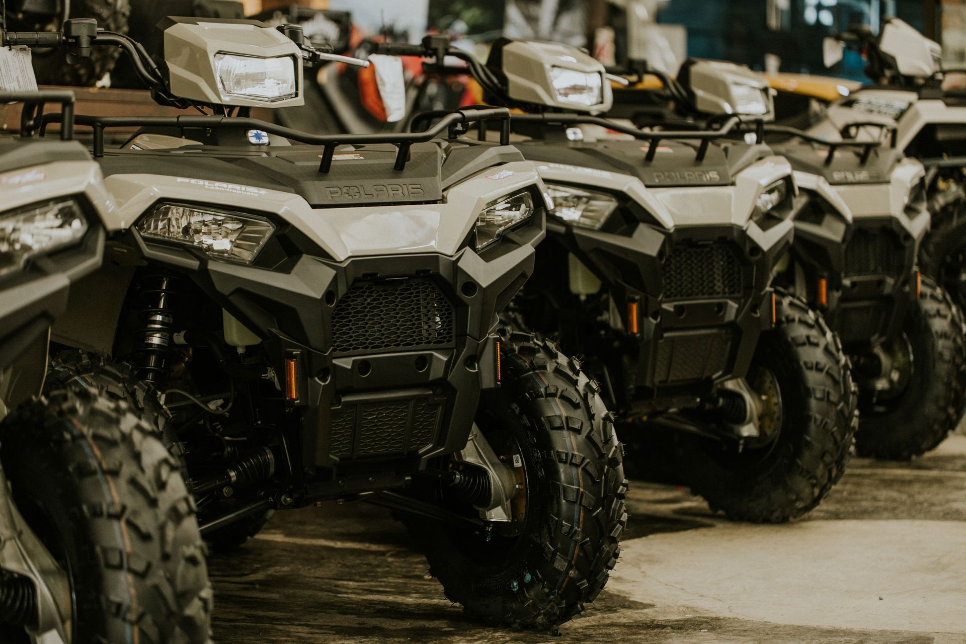 Row of rugged off-road ATVs parked indoors, front view with large knobby tires