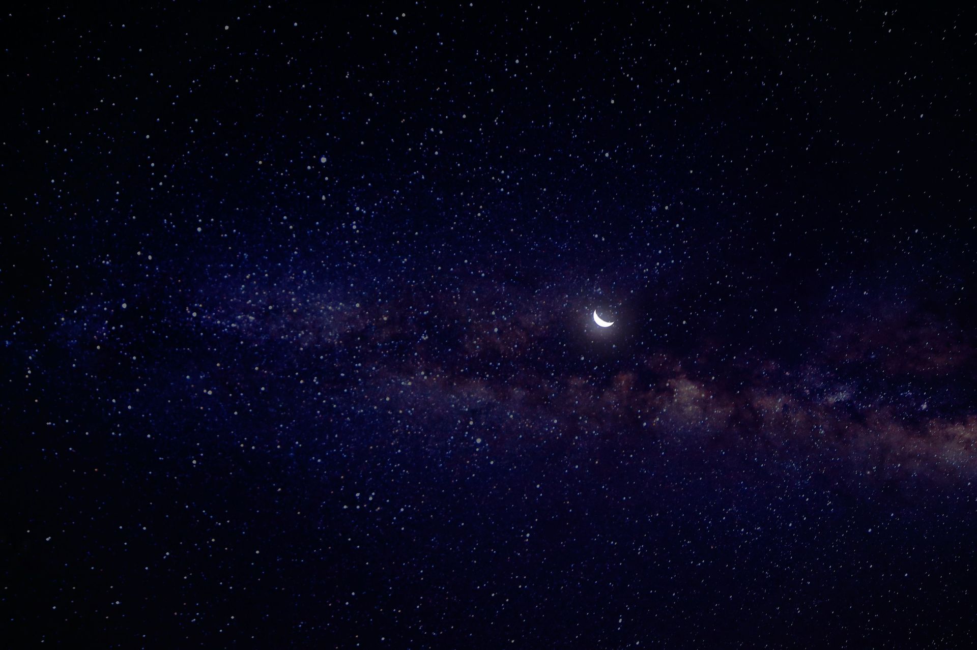 Starry night sky with a bright crescent moon and a faint Milky Way band
