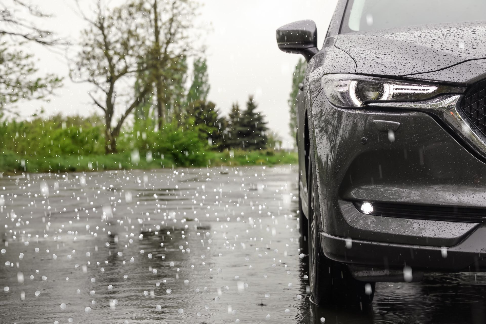 Close-up of a car in a storm as hailstones strike the road and vehicle exterior.