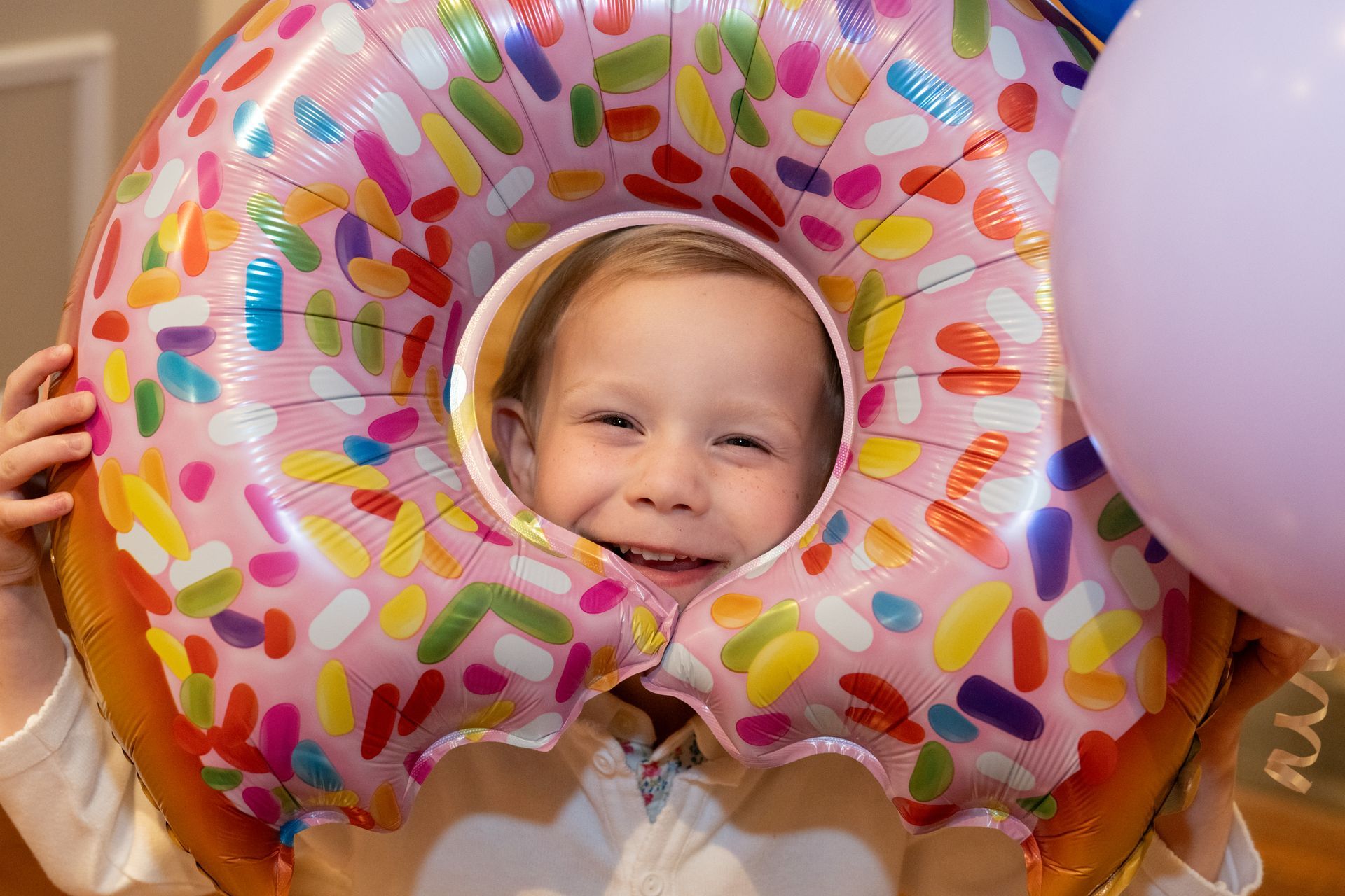 ShareBaby 2026 Diapers and Donuts Event - child putting face through a big donut balloon