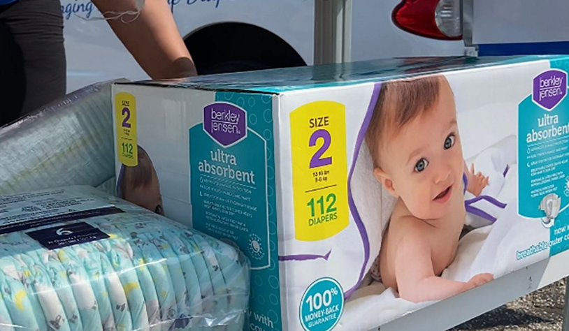 Boxed baby diapers in a store, with a smiling baby photo on the package and a price tag