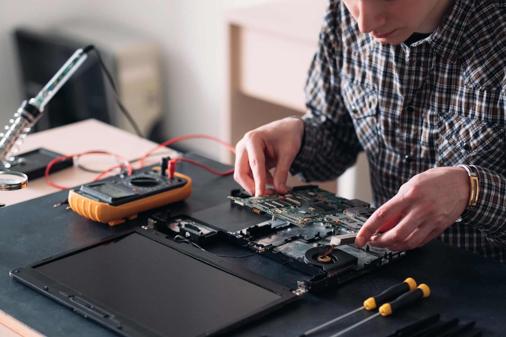 a man in a plaid shirt is working on a laptop computer