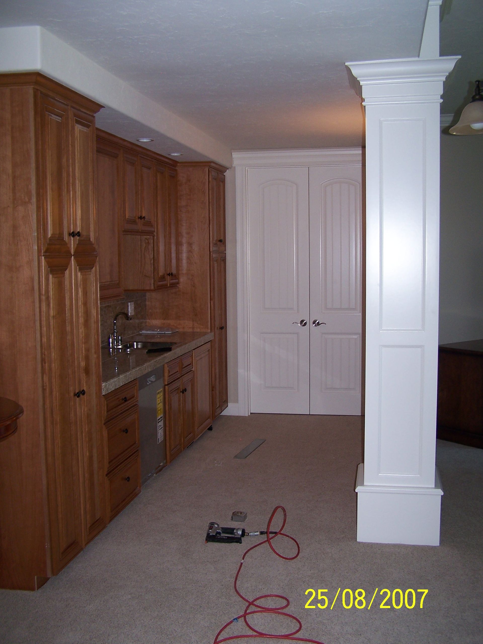 A kitchen with wooden cabinets and a white pillar