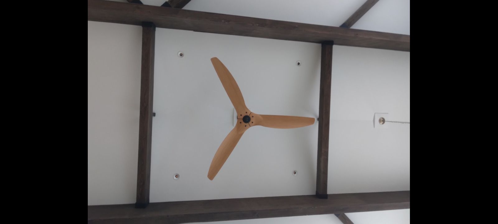 A wooden fan is hanging from the ceiling of a room.