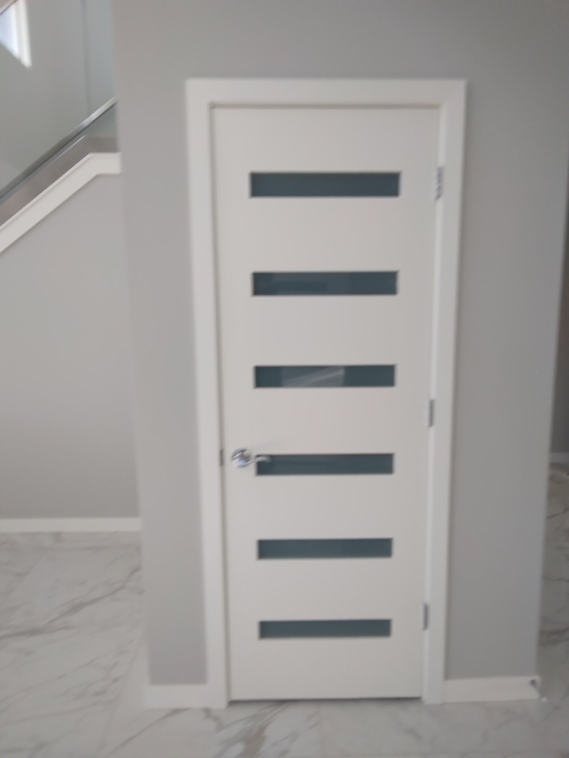 A white door with black stripes on it is in a room next to a staircase.
