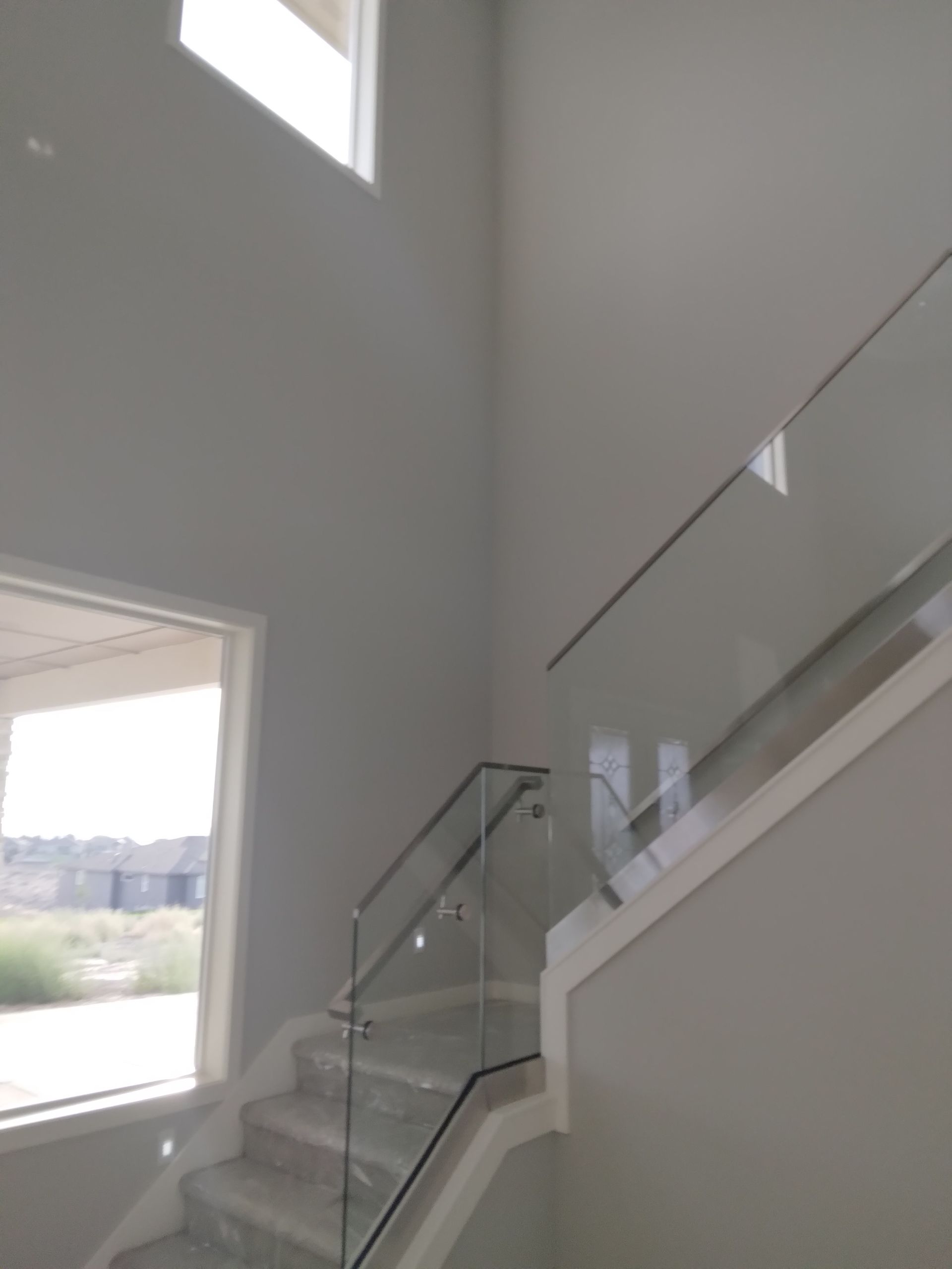 A staircase with a glass railing and a window