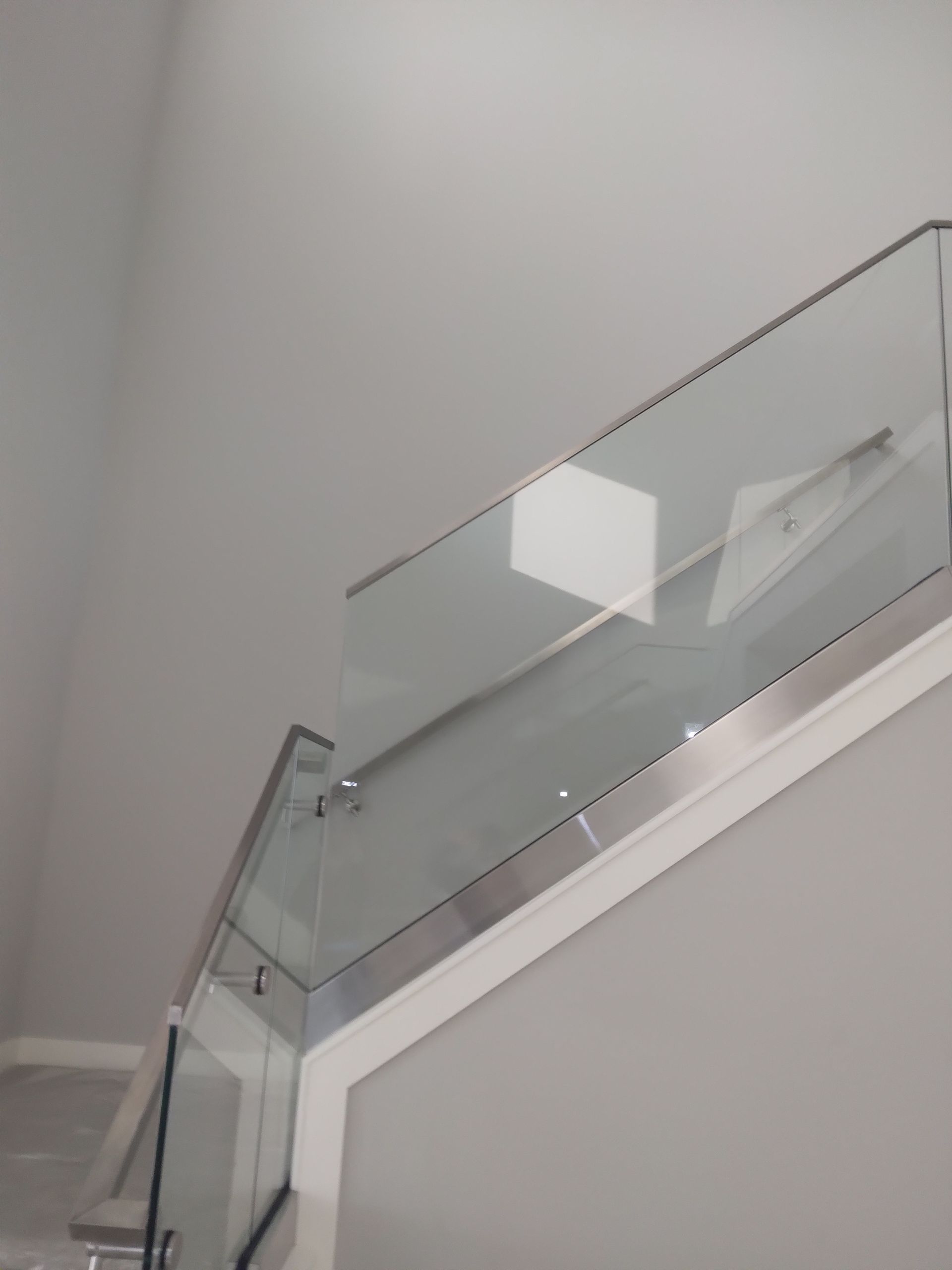 A staircase with a glass railing and a stainless steel railing.