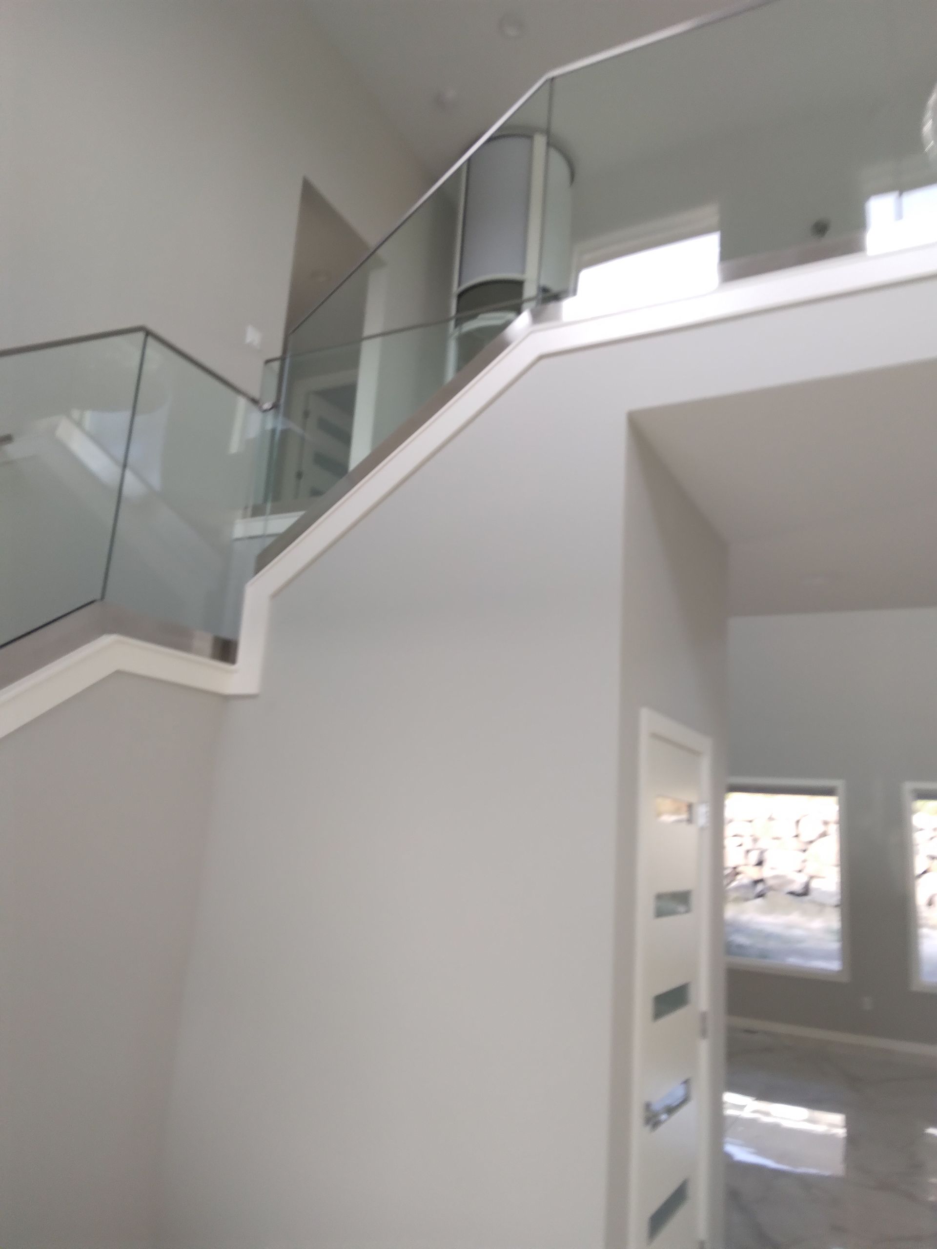 A staircase with a glass railing leading up to the second floor of a house.
