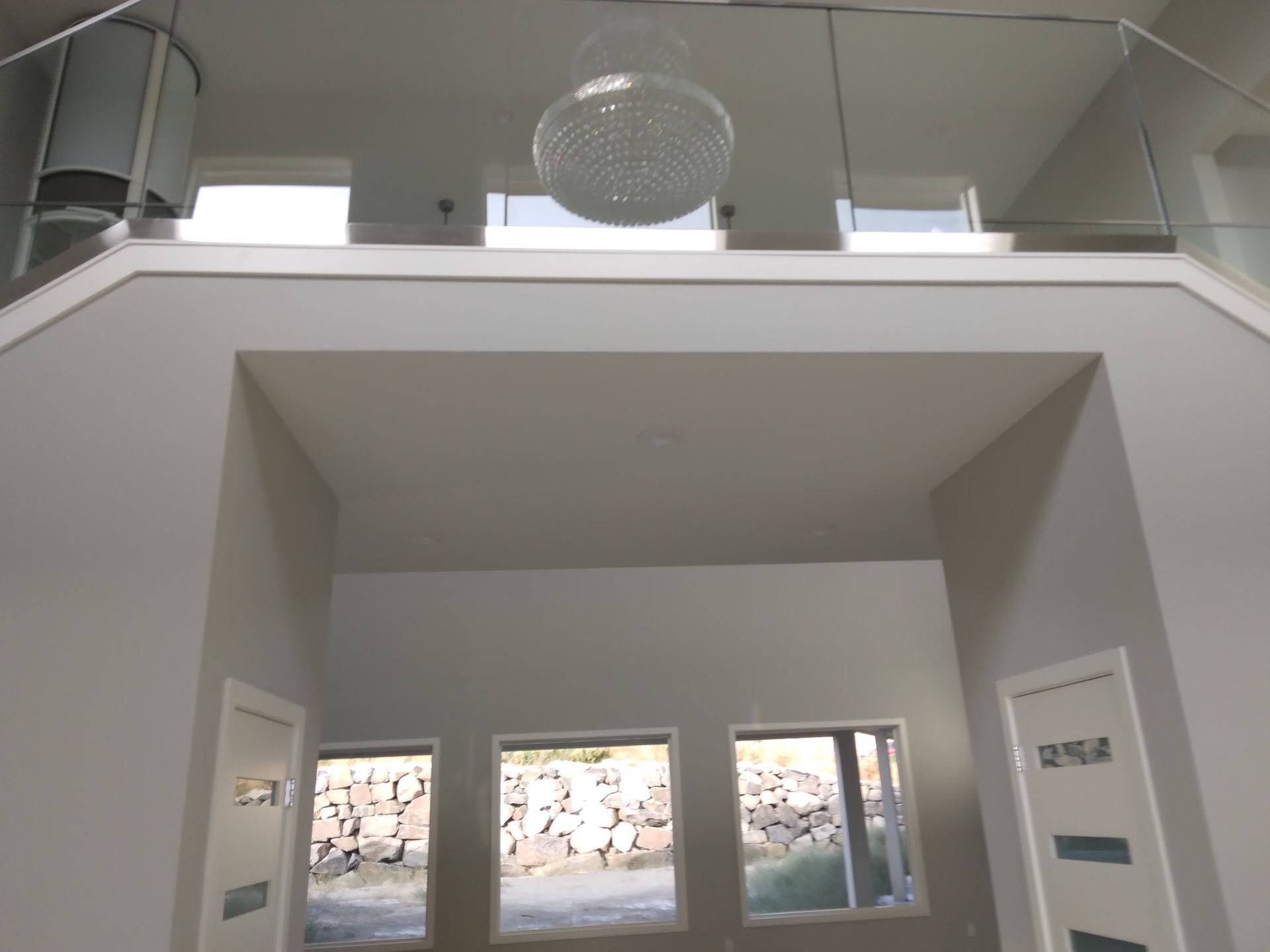 A staircase with a glass railing and a chandelier hanging from the ceiling
