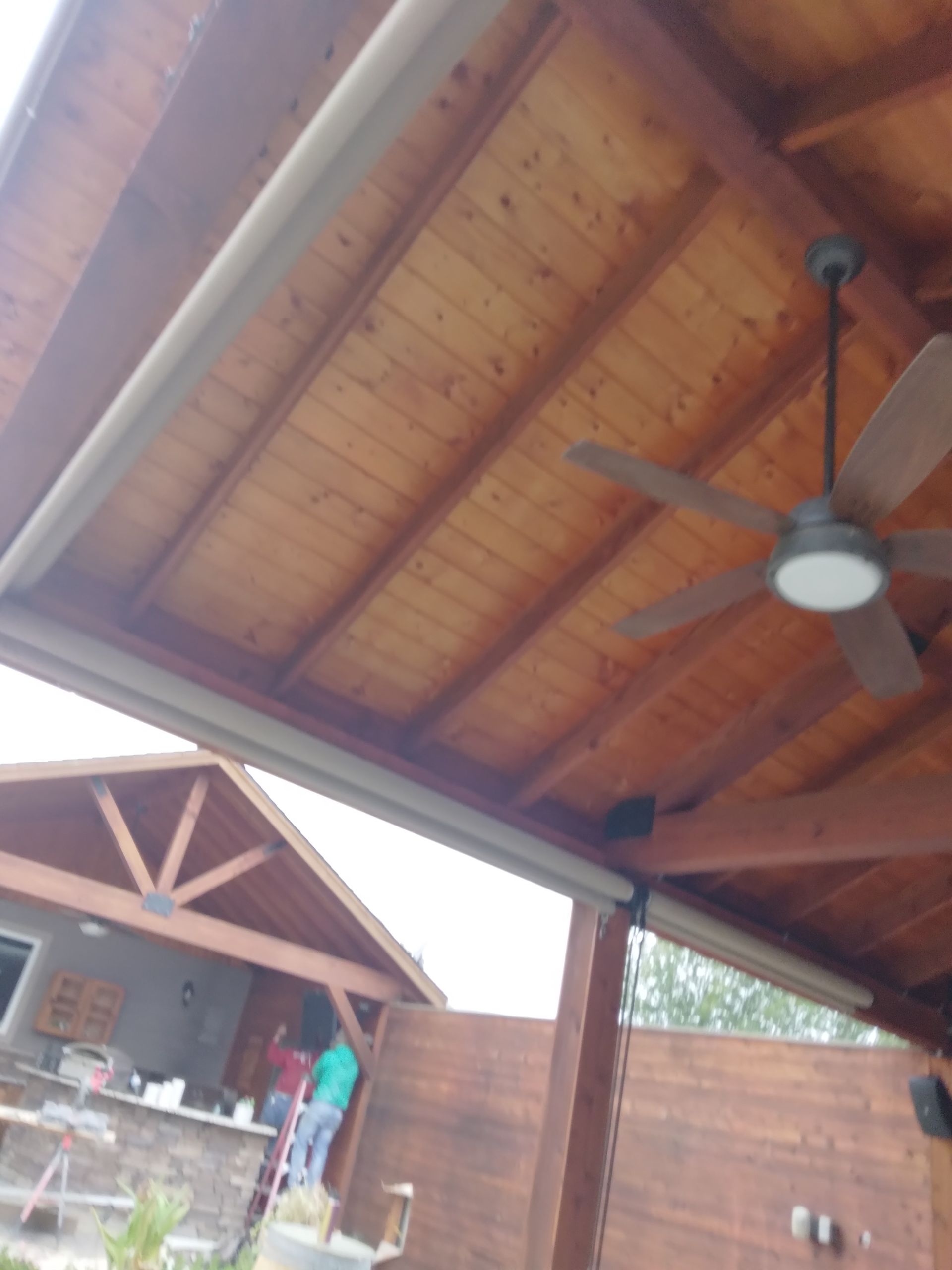 A ceiling fan is hanging from the ceiling of a wooden structure